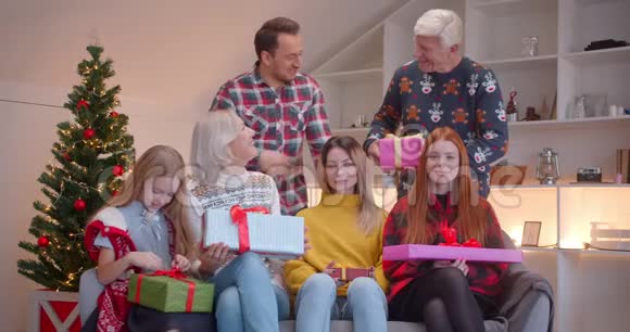 一家人坐在沙发上拿着圣诞礼物写着幸福视频的预览图