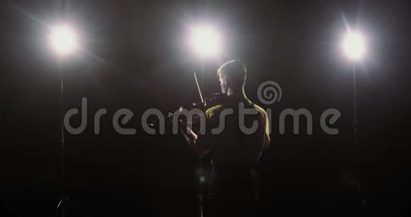 小提琴手的剪影在聚光灯下拉小提琴后视视频的预览图