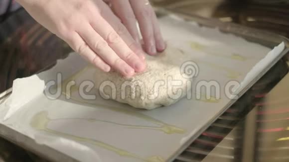 用橄榄油手工制作面团用手在薄烤饼纸上拉伸自制乡村披萨意大利烹饪时间视频的预览图