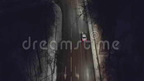 从无人驾驶飞机上看到汽车在夜间穿过森林的冬季道路上行驶视频的预览图