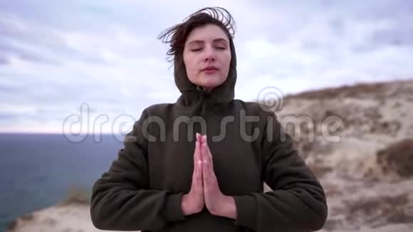 命名或祈祷积极的生活方式一个冷静的女人穿着运动衫把她的手掌放在一起在海洋上的悬崖视频的预览图