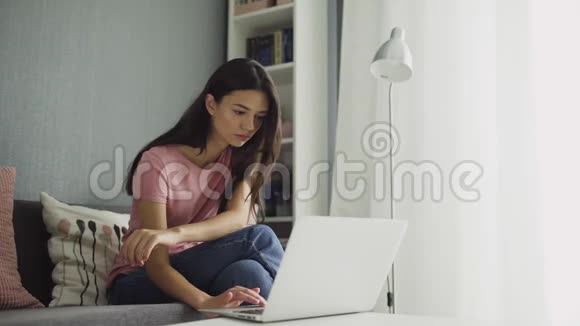 性感的女人带着笔记本电脑舒适地坐在家里视频的预览图