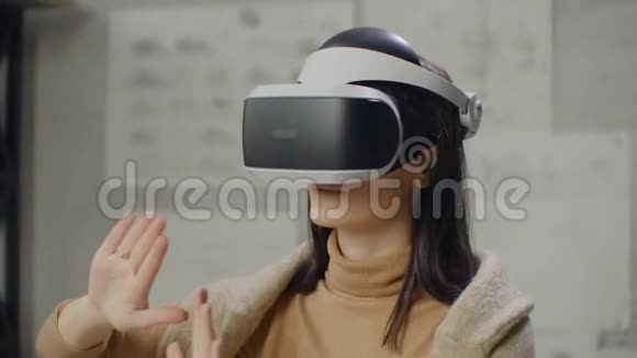 一个戴着虚拟现实头盔的女人背景是工作场所办公室里的一扇巨大的窗户设计视频的预览图