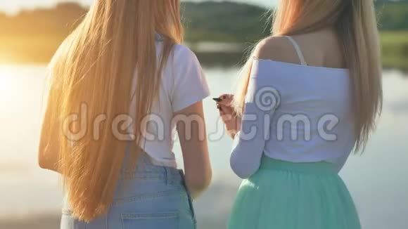 两个金发女孩背对着太阳站着说话视频的预览图