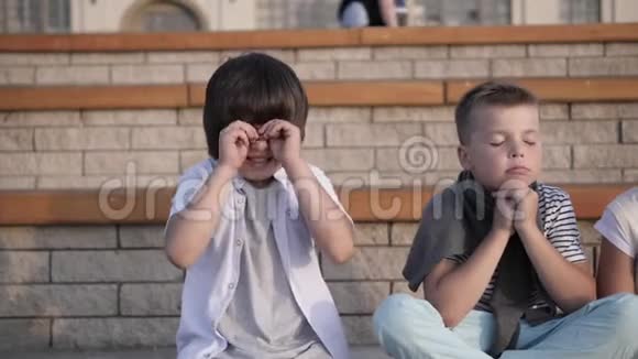 四个孩子看着无聊和过度疲劳的座位在长凳上视频的预览图