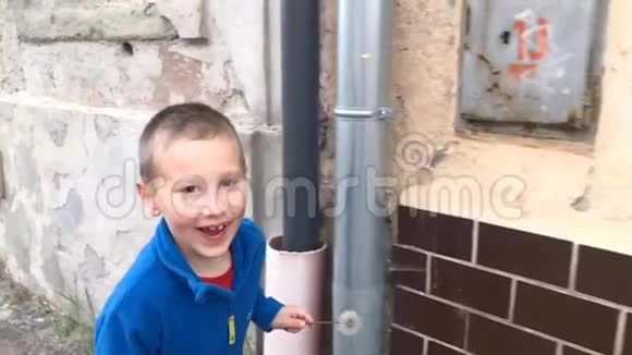 看着微笑的男孩独自跑过街道上破旧的墙视频的预览图