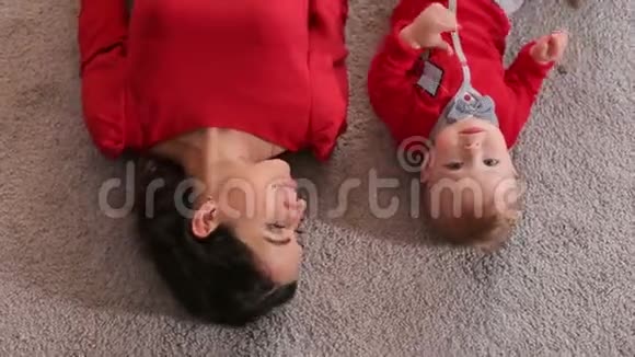 母亲和她的小儿子躺在房子蓬松的地毯上的俯视图视频的预览图