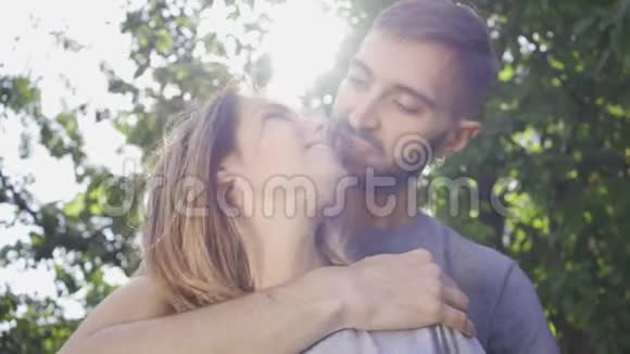 夏天花园里阳光下年轻人拥抱女朋友的肖像快乐的年轻家庭在户外休息视频的预览图