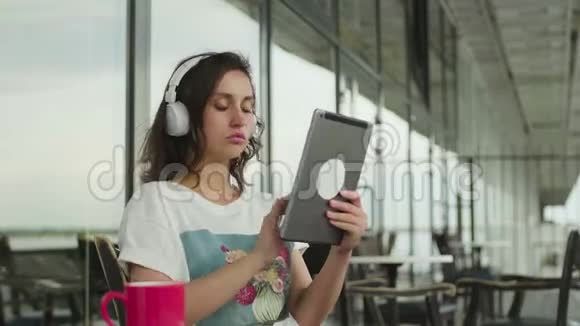 用平板电脑触摸屏替带耳机的欧洲女性微笑视频的预览图