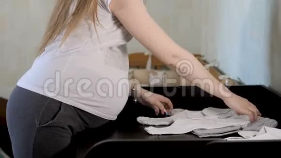 孕妇正在家婴儿的衣服放在换洗的桌子上视频的预览图