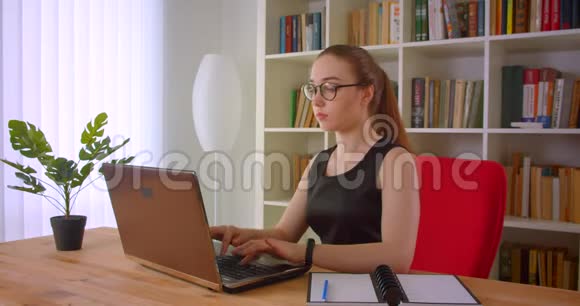 年轻漂亮的红头发女商人戴着眼镜手提电脑在办公室里体贴入微视频的预览图