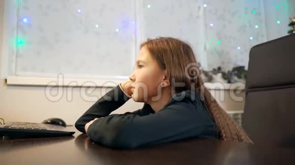 一个年轻的女孩坐着盯着显示器视频的预览图
