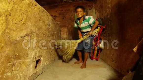 小印度男孩用扫帚破旧的房间自行车和木板在瓦拉纳西的一角贫民窟里清扫视频的预览图