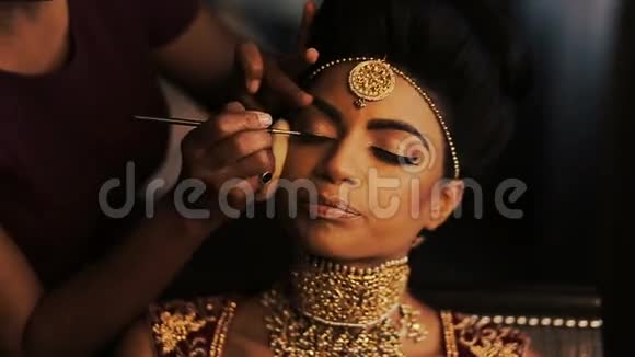 女人坐在椅子上平静地坐在印度新娘美丽的脸上化妆视频的预览图
