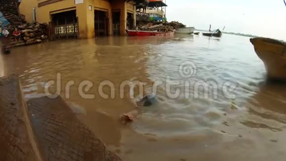 印度男孩来到肮脏的水面洪水圣河恒河船上和楼梯上成堆的紫檀木马尼卡尼卡盖特在O处视频的预览图