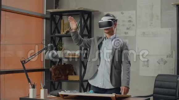 办公室里的男工程师戴着虚拟现实头盔用手势来管理项目而不离开办公室视频的预览图
