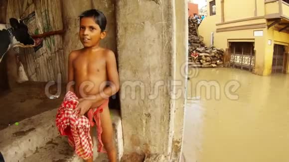 小印度男孩在楼梯上用干净的红色物质脏水洪水圣河恒河成堆的紫檀木擦拭他湿漉漉的身体视频的预览图