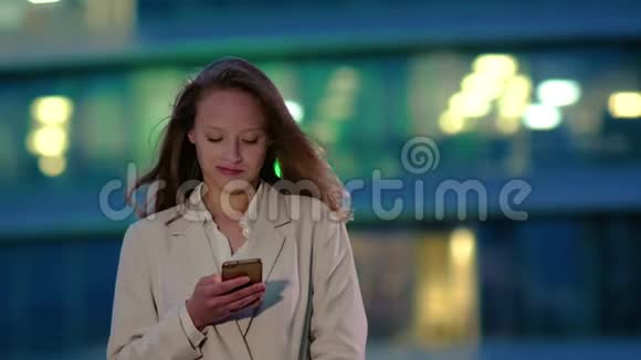 年轻女孩晚上在智能手机上读信息视频的预览图
