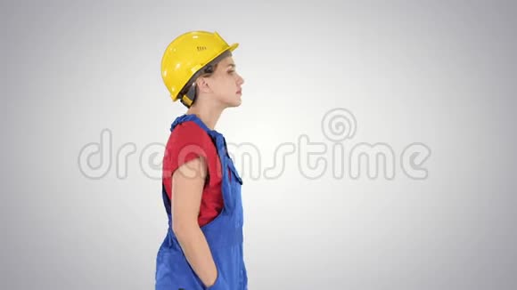 建筑工人女士在梯度背景下无感情地行走视频的预览图