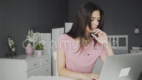 年轻迷人又无聊的女人在卧室里做笔记本电脑视频的预览图