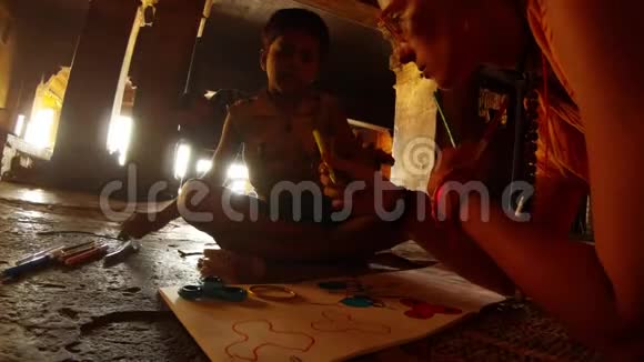 白人妇女和印度小男孩在瓦拉纳西的黑暗房间里用毛毡笔画视频的预览图