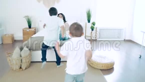 两个快乐的男孩在卧室里跑着拥抱妈妈视频的预览图
