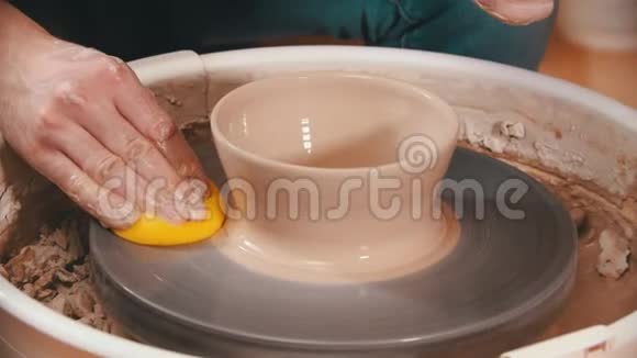 陶器主人正在用黄色海绵擦拭陶器的轮子视频的预览图