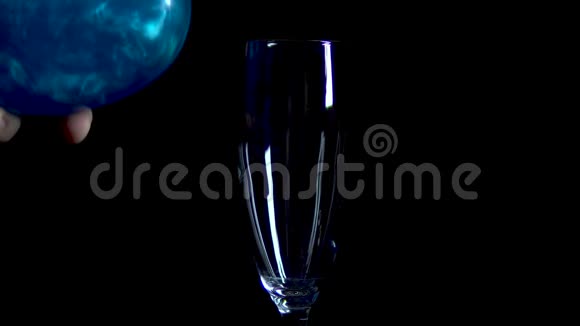 一杯蓝色的饮料倒在黑色的背景上灵丹妙药旋转和闪烁爱的感情是孤立的视频的预览图