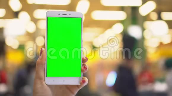 女人专注于她的智能手机同时显示一个绿色屏幕集中在她设备的屏幕上铬键视频的预览图
