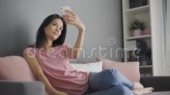 漂亮的女人坐在沙发上用手机自拍视频的预览图