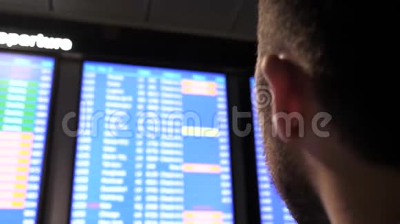 年轻的商人在机场看着有航班时间表的飞机视频的预览图