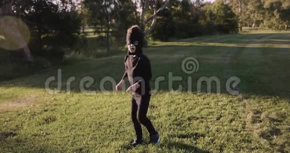 小男孩戴着自制的忍者面具穿着黑色服装在公园里练习忍者动作忍者转身和踢到一边视频的预览图