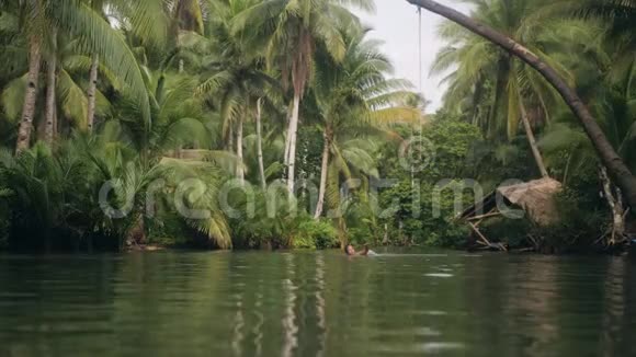 一个女人在一条被热带树叶环绕的河流中游泳视频的预览图