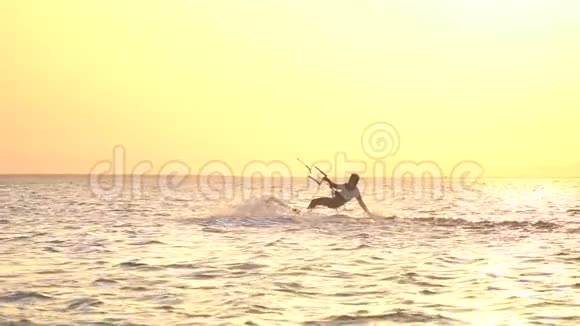 风筝冲浪者正在大海中做背卷背景上灿烂的日落视频的预览图