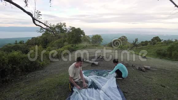 一对夫妇在山上的一个露营地搭起一个帐篷可以看到希格兰的景色视频的预览图