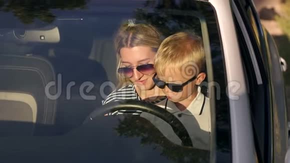 妈妈和儿子戴着太阳镜坐在车轮边视频的预览图