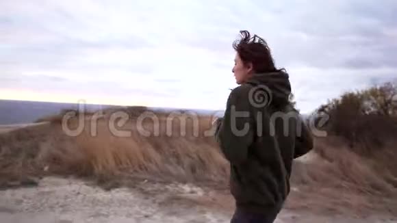 在阴天日落时身材苗条的女人在海边的悬崖上慢跑耐力训练准备视频的预览图
