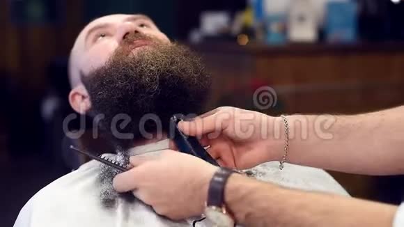 专注于现代理发店剪卷发暗胡须的过程男性手使用电动修边器和梳子视频的预览图