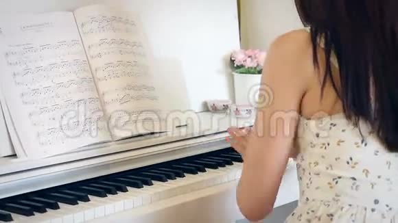 年轻女子在明亮的房间里弹钢琴手握着视频的预览图