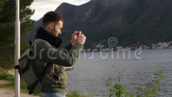 男性游客正在观看海景并使用手机拍照黑山视频的预览图