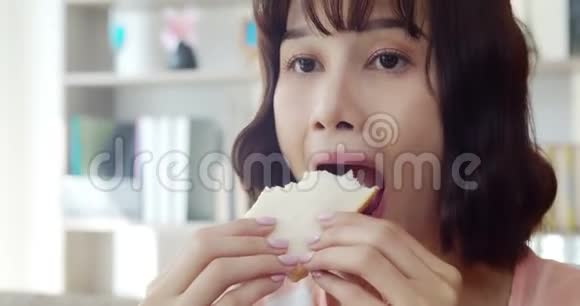 年轻女人咬着吃一个大三明治和美味视频的预览图