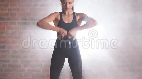 运动的女人站着拿着水壶铃美丽的白种人女人训练二头肌视频的预览图
