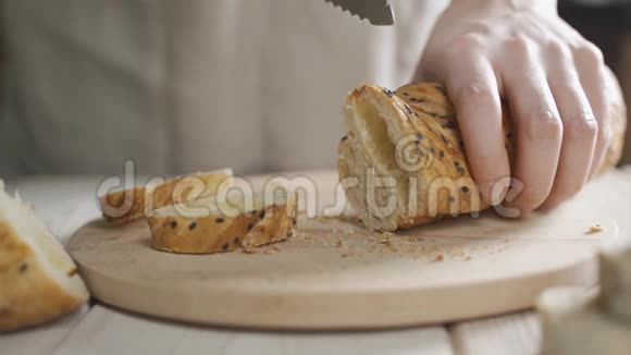 在桌上用黑芝麻切片面包巴盖特传统法国面包在桌子上切割特写视频的预览图