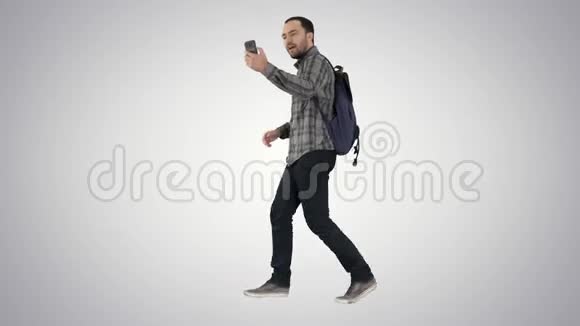 年轻快乐的微笑男子背包记录vlog博客与他的手机梯度背景视频的预览图