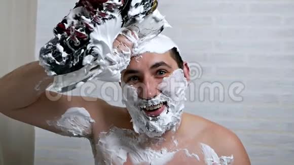 一个奇怪的人用剃须泡沫和冰鞋把头发剃在头上用刀片把头发从头上刮下来视频的预览图