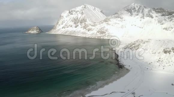 冬季挪威北部洛福滕岛豪克兰海滩的空中录像雪山在阳光下闪闪发光通常情况下视频的预览图
