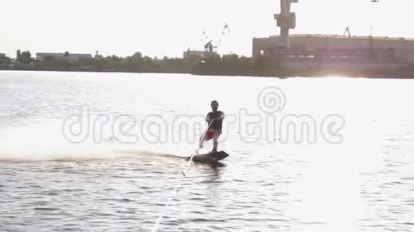 阳光下的运动者乘坐摩托艇后的尾板在大自然的背景下沿着河流溅起水花视频的预览图