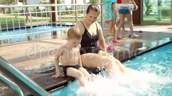 有趣的妈妈和儿子在游泳池里玩他们溅起了脚视频的预览图