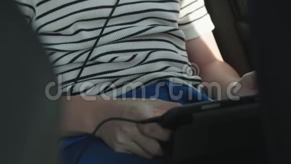 开车时带着耳机玩平板电脑和智能手机的男孩视频的预览图