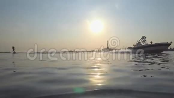 Wakesurf阳光明媚的夜晚酷酷的运动员在蓝色的河上乘着溅满水的船视频的预览图